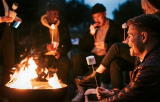 People gathered around a campfire during a recovery alumni event